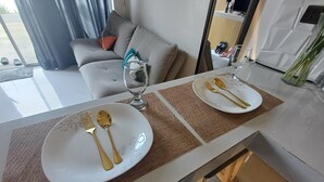 A dining table set with white plates, gold cutlery, and a wine glass. - The Most Romantic Staycation in the City (Tacloban City)