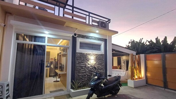 A modern house with a glass door entrance, a balcony, and a parked scooter. - The Most Romantic Staycation in the City (Tacloban City)