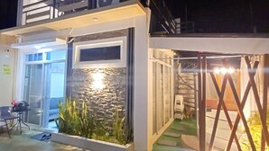 A modern building with a glass entrance, a small outdoor seating area, and a water feature. - The Most Romantic Staycation in the City (Tacloban City)