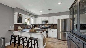 A modern kitchen with a central island, stainless steel appliances, and white cabinetry. - Weitz Haven: Pool, Hot-tub, More! (Fredericksburg)