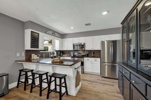 A modern kitchen with a central island, stainless steel appliances, and white cabinetry.