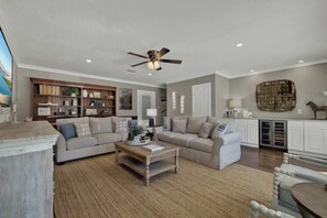 A living room with a sofa set, a coffee table, a ceiling fan, and a bookshelf.