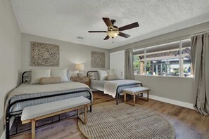 A bedroom with two beds, a ceiling fan, and a large window with a view of the outdoors. - Weitz Haven: Pool, Hot-tub, More! (Fredericksburg)