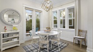 Un espace repas comprenant une table ronde, des chaises blanches, un tapis noir et blanc et un lustre aux motifs géométriques.