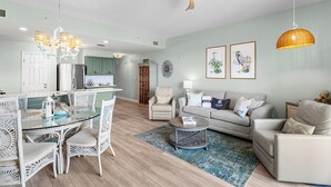 A spacious living area with a dining table, chairs, a sofa, and a ceiling fan. - Beach Resort 402 - Gulf View, Zero-Entry Lagoon Pool, Hot Tub, Deeded Beach! (Miramar Beach)