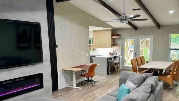 A modern living room with a large grey sectional sofa, a flat-screen TV mounted on the wall, and a ceiling fan. - Family & Pet Friendly Home in Boca Raton w fenced backyard, jacuzzi & playground (Boca Raton)