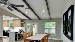 A modern kitchen with a central island, a dining area with a wooden table and orange chairs, and a ceiling fan. - Family & Pet Friendly Home in Boca Raton w fenced backyard, jacuzzi & playground (Boca Raton)