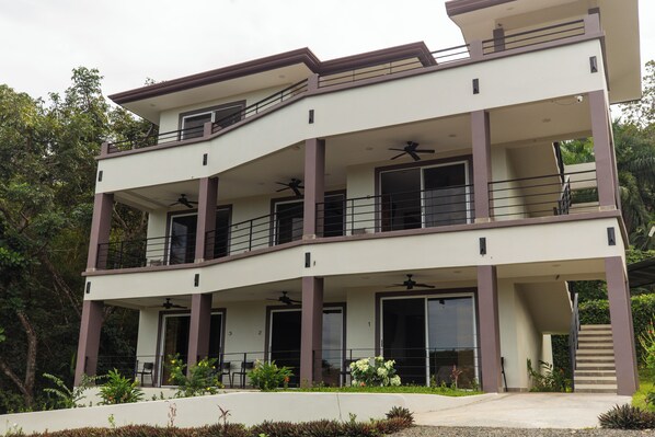 A multi-story building with balconies, large windows, and a staircase.