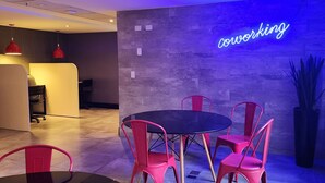 Un espace de coworking moderne, doté d'un néon, de tables rondes et de chaises rouges.