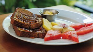A hand pouring syrup over a steak and toast, with a side of fruit and a small bowl of butter on a plate. - 6 room villa with rooftop terrace in Playa Coyote, Six room villa with pool, bar, and restaurant. Oc (San Francisco de Coyote)