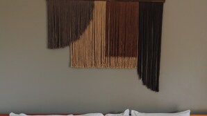 A bed with white pillows and a teal accent pillow, a textured white bedspread, and a wall with a wooden headboard and a decorative fringe hanging above. - 6 room villa with rooftop terrace in Playa Coyote, Six room villa with pool, bar, and restaurant. Oc (San Francisco de Coyote)