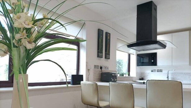 Eine moderne Küche mit einer zentralen Kochinsel, Barhocker und einer Vase mit Blumen auf dem Tisch.