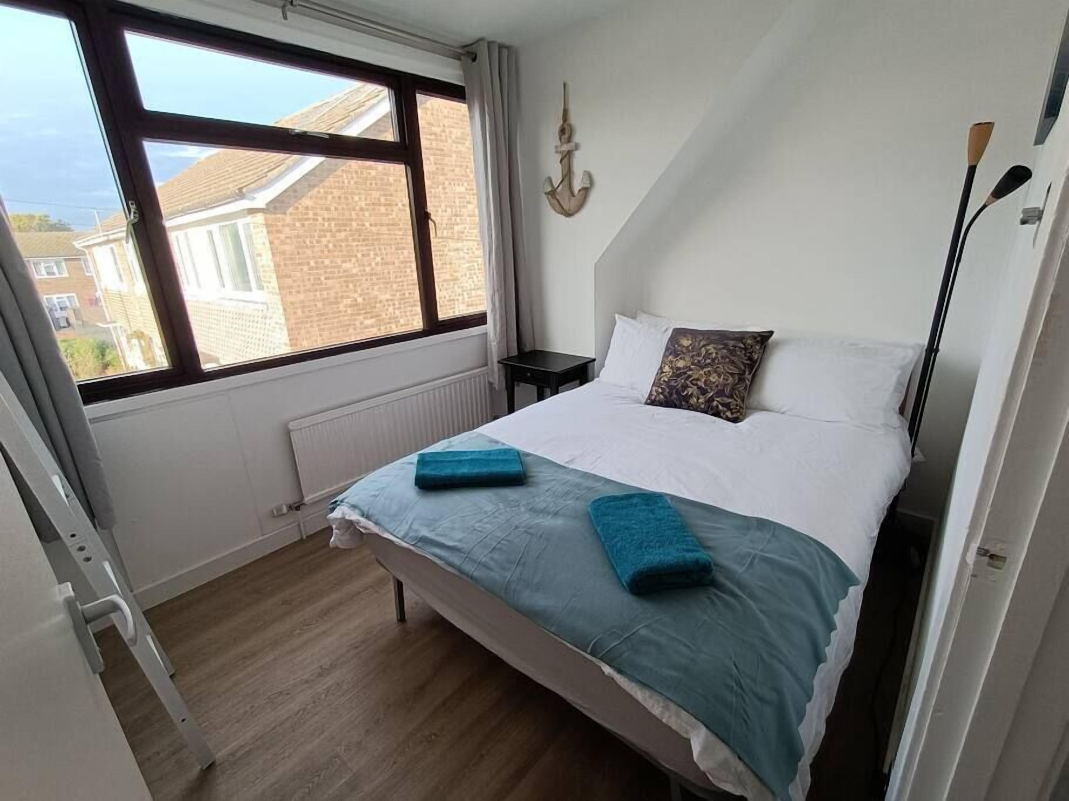 A bedroom with a bed, a window, a radiator, and a wall-mounted light fixture.