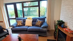 Ein Wohnzimmer mit einem dunkelblauen Sofa, einem Holztisch und einem schwarzen Sessel.