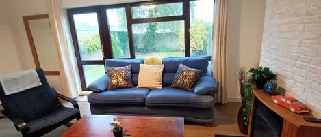 A living room with a dark blue sofa, a wooden coffee table, and a black armchair.