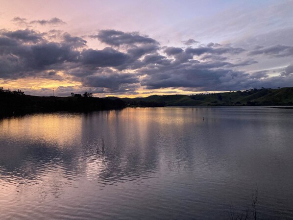 A calm lake with a sunset sky and hills in the background.