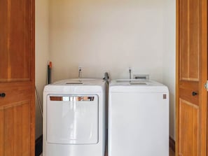 Two white washing machines in a small room with wooden doors.
