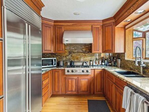 A kitchen with wooden cabinets, a stainless steel refrigerator, a stove, and a microwave.