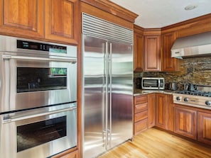 A kitchen with wooden cabinets, stainless steel appliances including a refrigerator, oven, and microwave, and a gas stove.