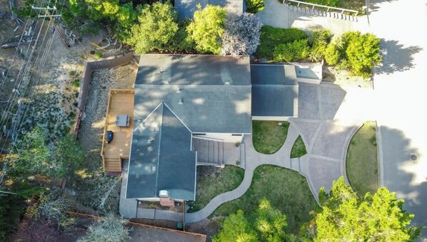 An aerial view of a residential property with a large house, a driveway, and surrounding greenery.
