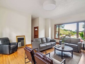 A spacious living room with a grey sofa set, a black leather armchair, and a coffee table.