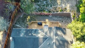 Et moderne hus i to etager med skråt tag, en overdækket terrasse og en anlagt have med en snoet sti.