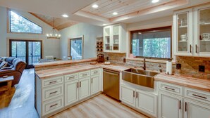 Une cuisine moderne avec des meubles en bois, un évier en acier inoxydable et une grande fenêtre donnant sur une forêt.
