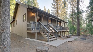 Une cabane avec une façade en bois, une véranda dotée d’une balustrade et un escalier menant à l’entrée.
