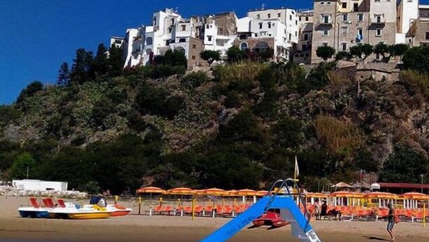Un barco amarrado cerca de una playa, con edificios al fondo.