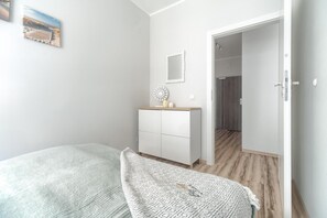 Ein Schlafzimmer mit einem Bett, einem Schminktisch, einem Spiegel und einer Tür zu einem anderen Raum.