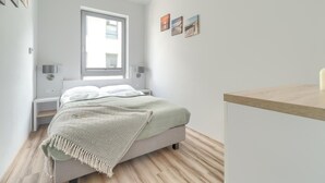 A bedroom with a bed, bedside tables, a window, and wall art.