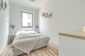 A bedroom with a bed, bedside tables, a window, and wall art.