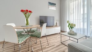 A modern living room with a dining table, chairs, a flat-screen TV, and a sofa.