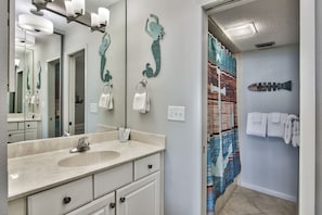 Une salle de bain avec un grand miroir, un lavabo et des porte-serviettes.