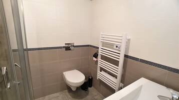 Ein Badezimmer mit Toilette, Waschbecken, Duschkabine aus Glas und Handtuchhalter.
