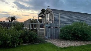 Een rustiek houten gebouw met een bord waarop staat: Welkom bij De Bijenkorf.