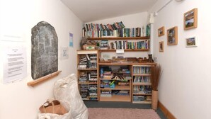 Een kamer met een boekenplank vol boeken, een schoolbord aan de muur en een plastic tas op de vloer.