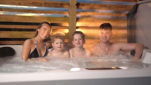 Une famille dans un bain à remous, avec des lattes de bois en arrière-plan.