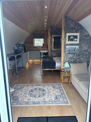 A cozy interior with a bed, a sofa, a rug, a kitchen area, and a dining table. - The Galloway Steading-The Herons Nest cabin with Hot Tub couples/families (Glenluce)