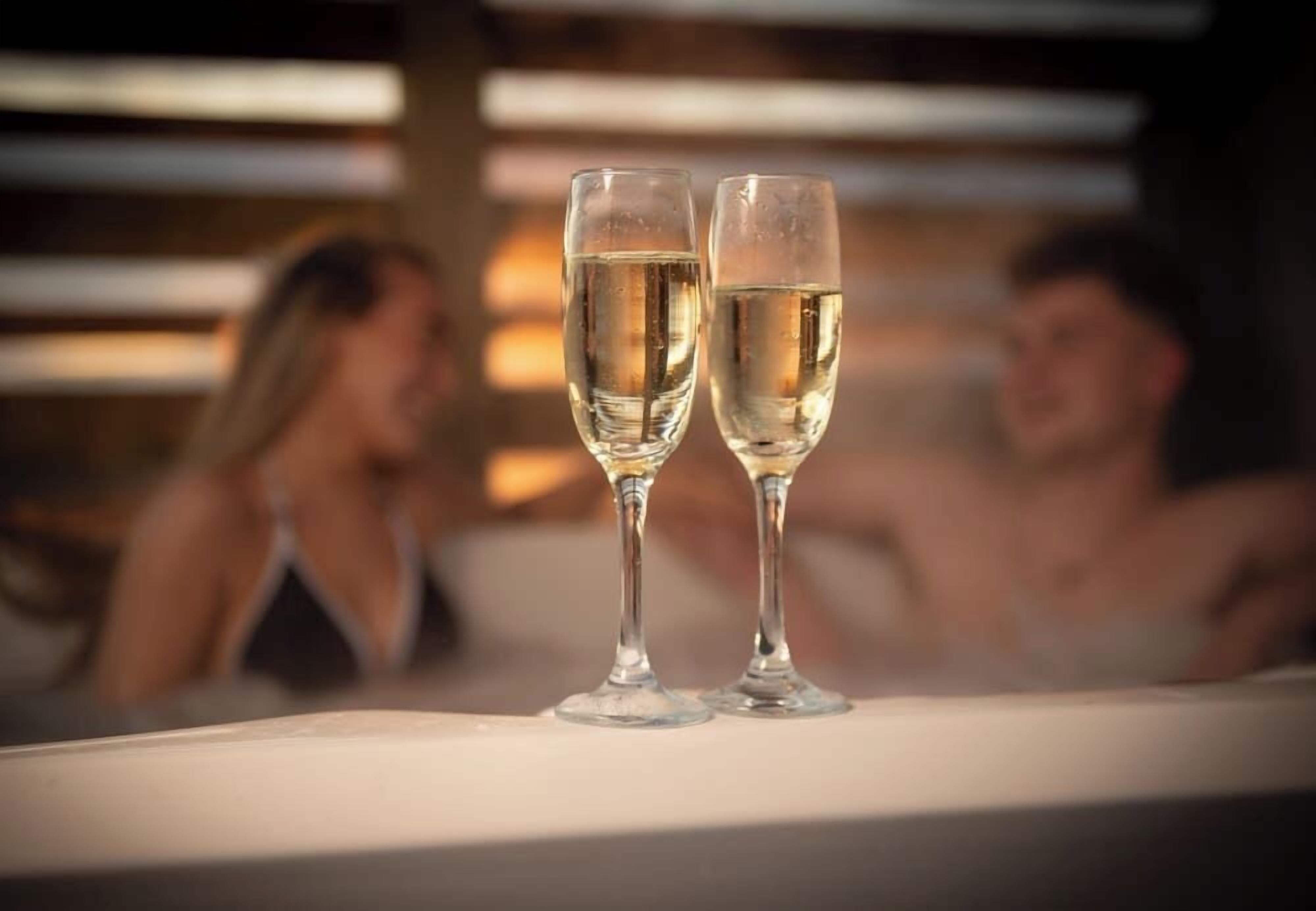 Two glasses of champagne on a table in a dimly lit room.