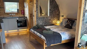 Une chambre confortable avec un lit, une table de chevet, un miroir et un plafond en bois.