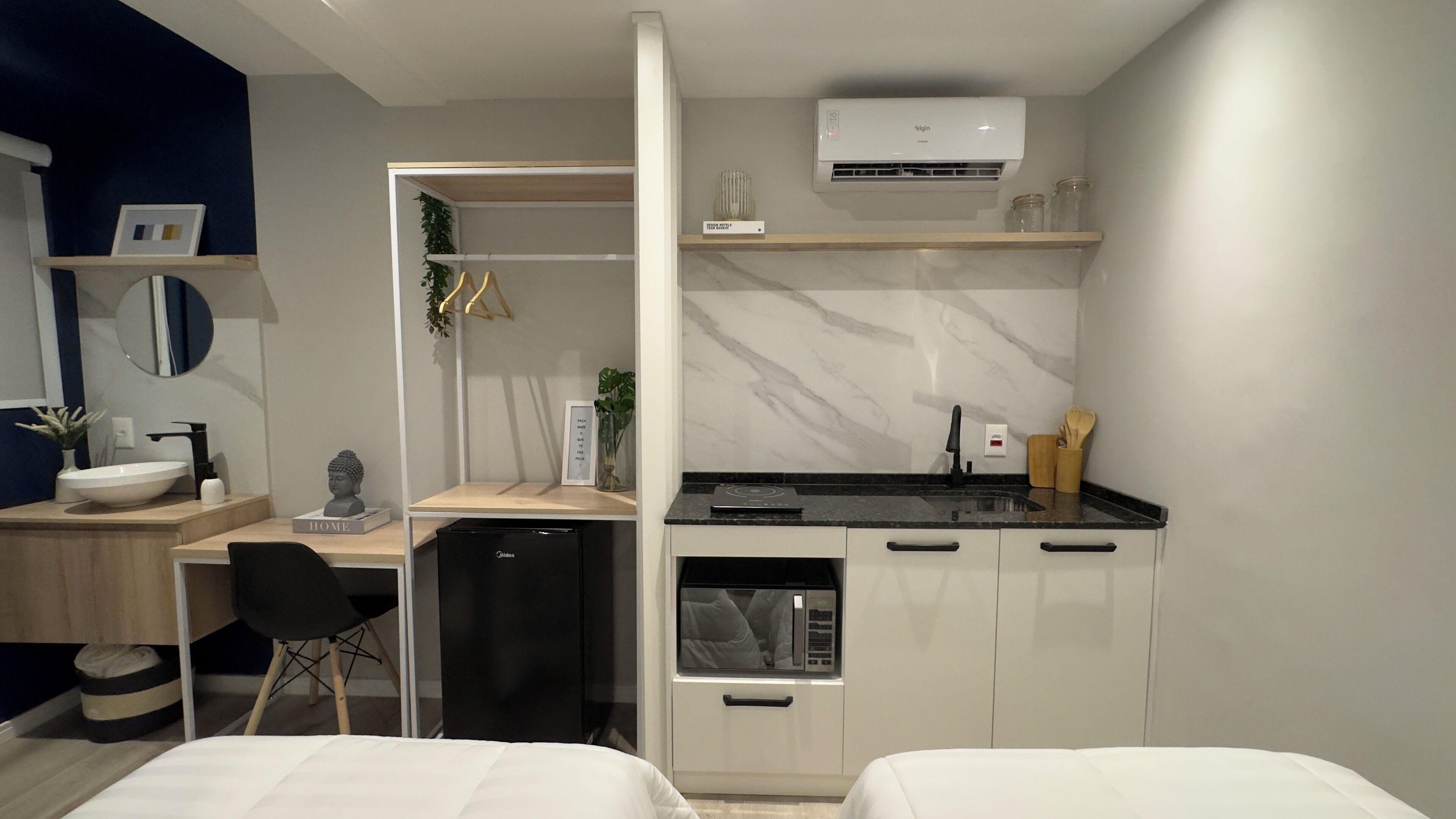 Habitación de hotel compacta con kitchenette, un pequeño comedor y una cama.