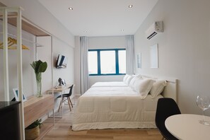 A modern hotel room with a large bed, a desk, a chair, and a small table with a glass. - Apê Pátio Paulista  (São Paulo)