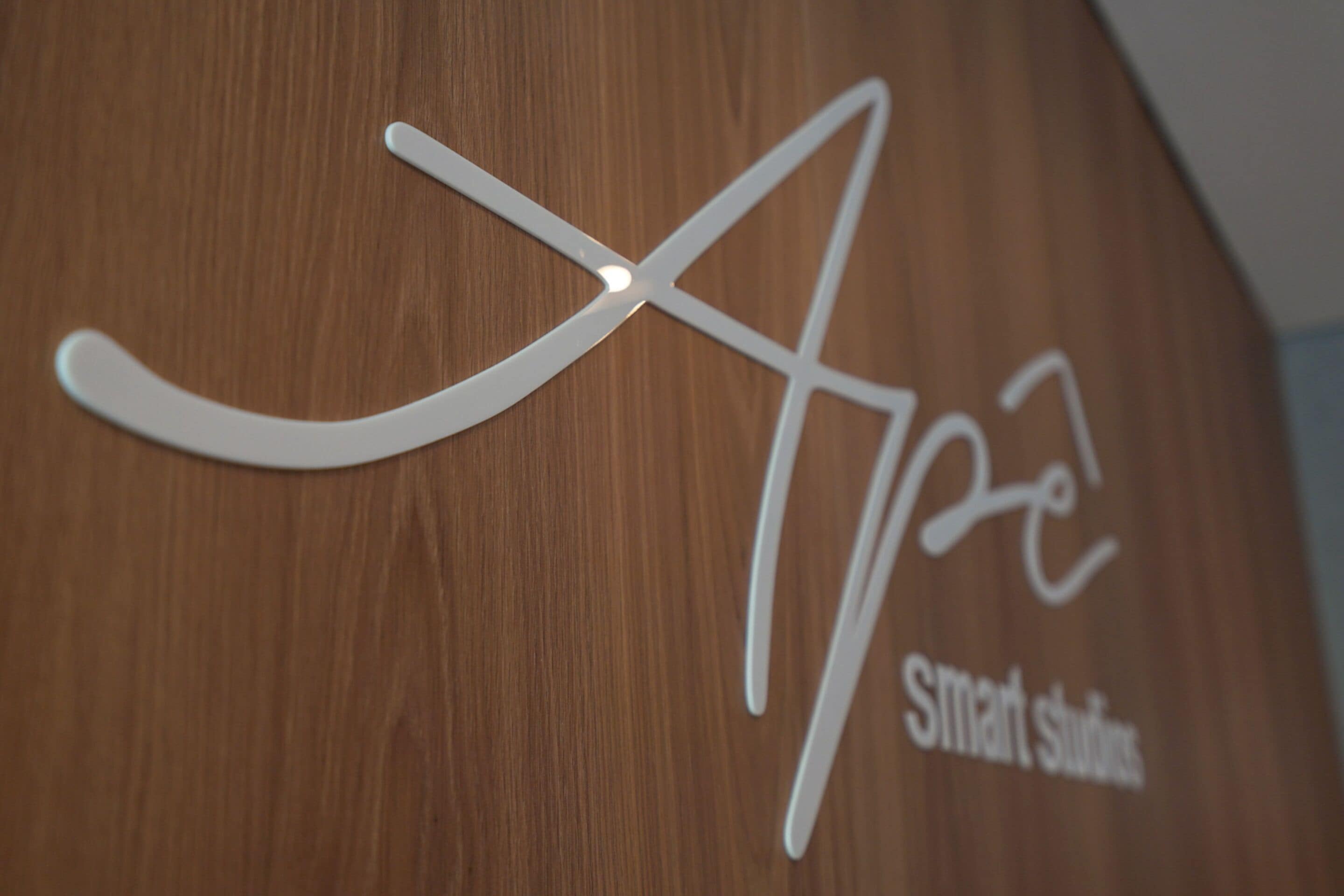 Een houten wand met een wit logo en de tekst 'Smart Studios'.