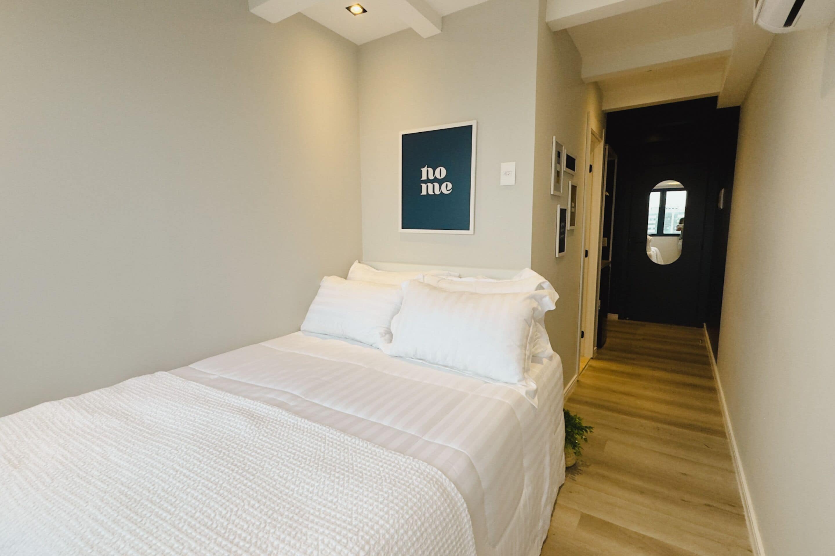 Une chambre à coucher avec un lit, un tableau encadré au mur et un couloir menant à une porte.
