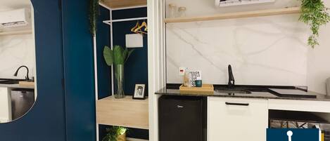 A modern kitchen with a built-in dishwasher, a marble backsplash, and a small refrigerator.