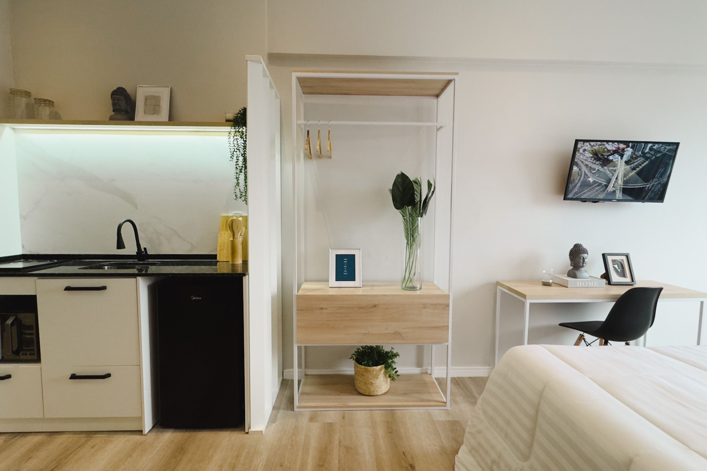 A compact, modern room with a kitchenette, a small desk, and a bed.