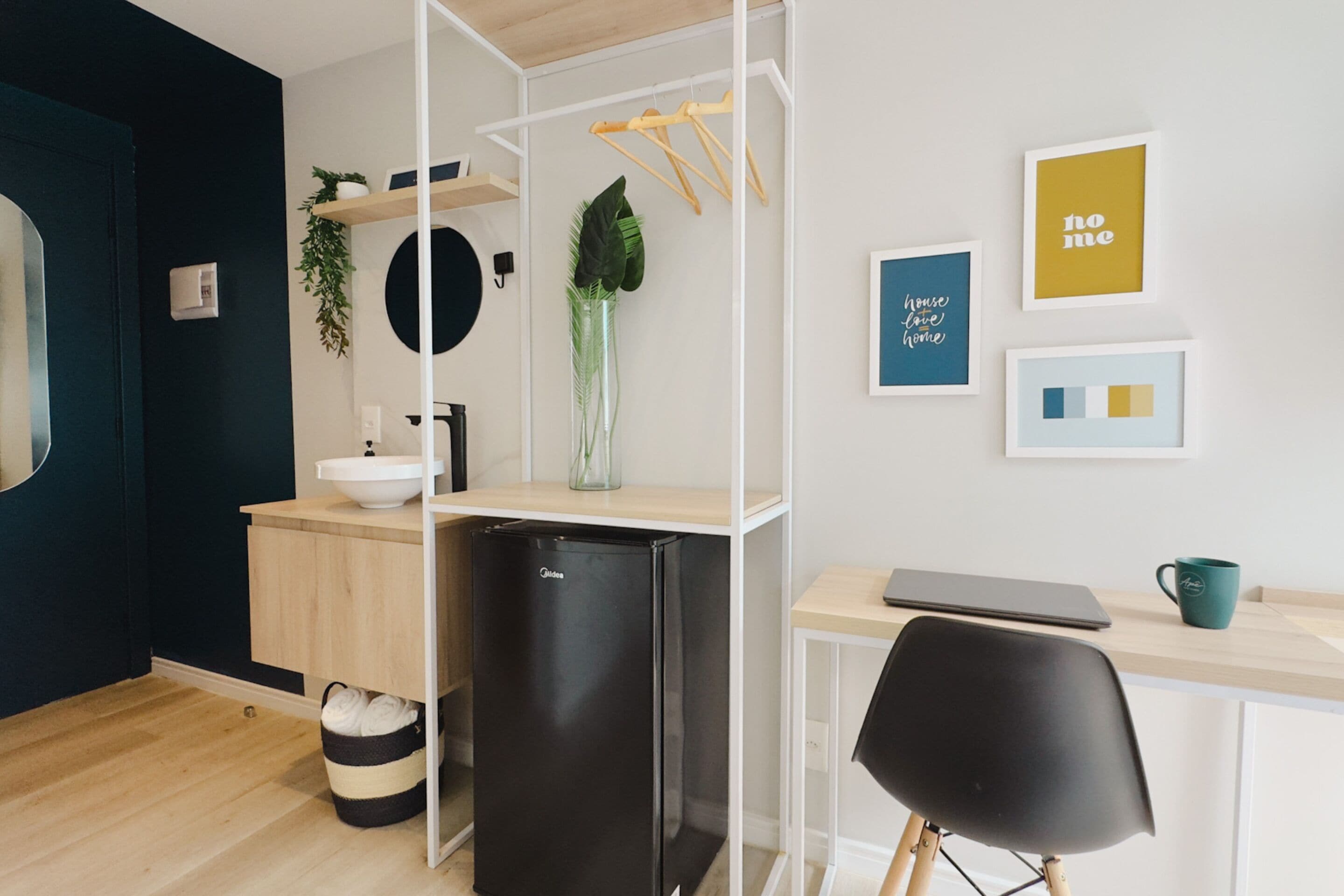 A modern kitchen with a black refrigerator, wooden cabinets, and a sink. There is a plant on the counter and a hanging plant on the wall.