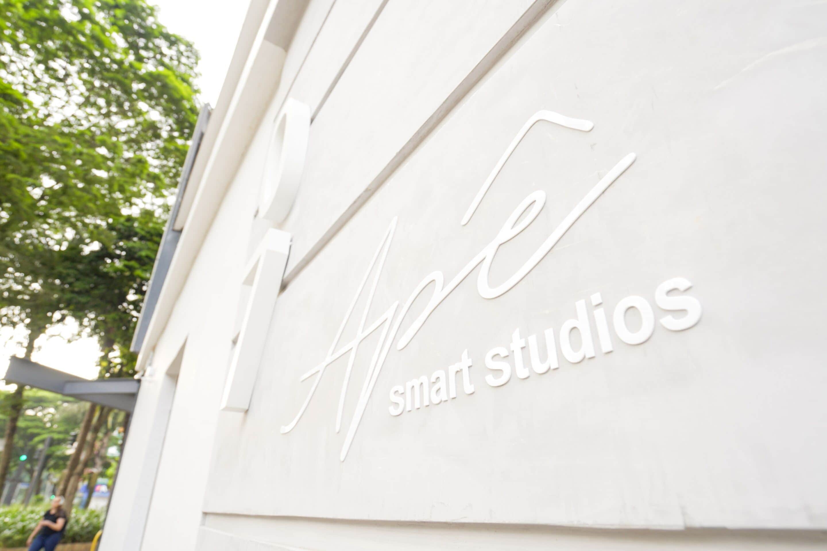 A sign with the text "APE smart studios" on a white wall.