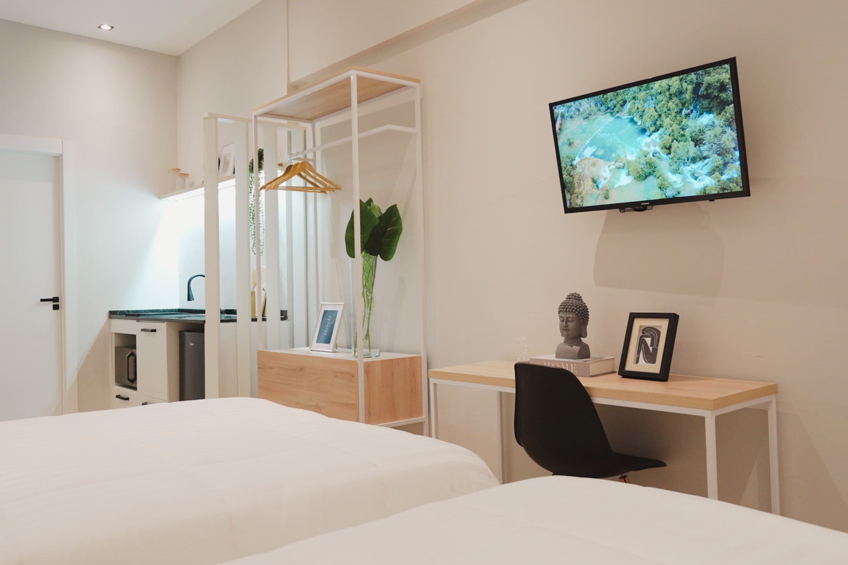 A modern hotel room with two beds, a desk, a chair, a TV, and a wardrobe.